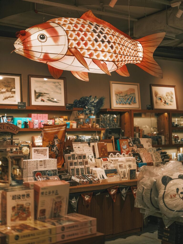 Interior of a unique bookstore featuring a large hanging fish decoration and various art pieces.